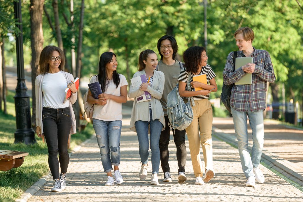 Multiethnic group young cheerful students walking